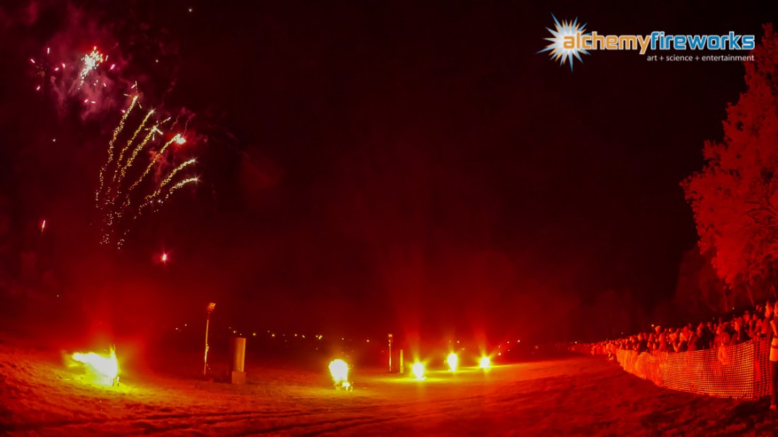 Red flares light up an audience watching fireworks