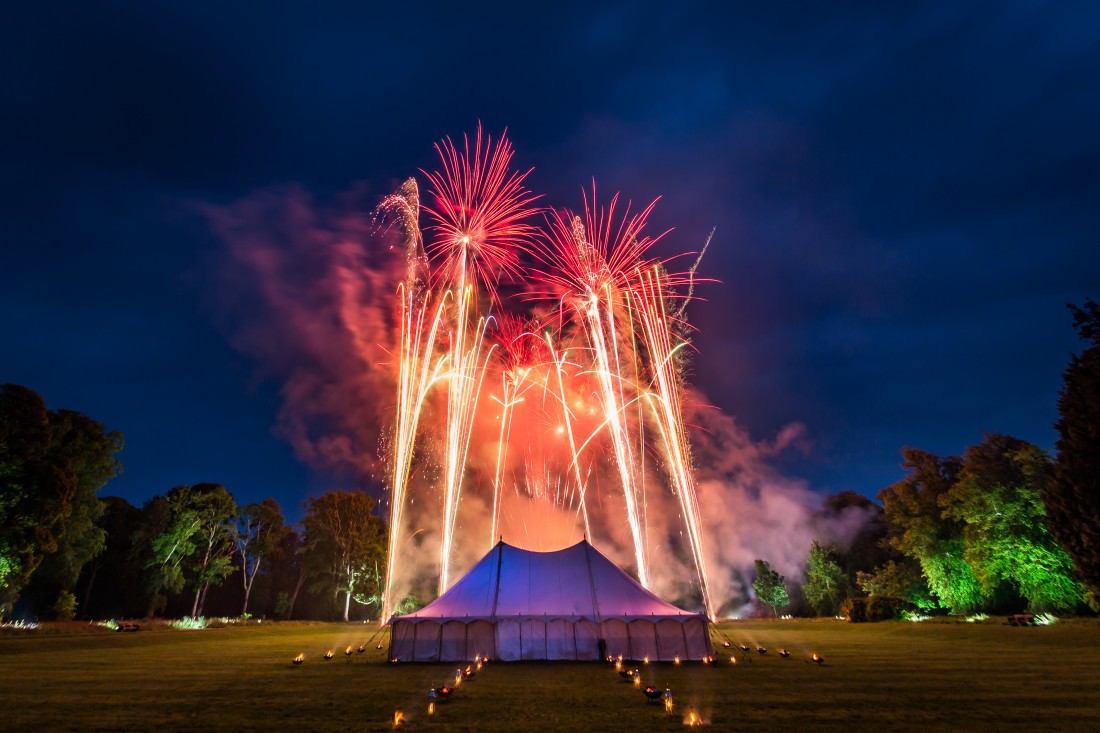Silver trails and red bursting fireworks above a marquee in Scotland