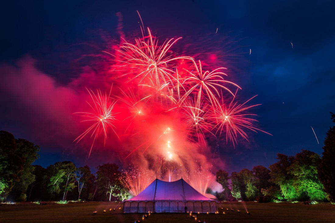 Bright red fireworks bursting over a marquee on the Isle of Bute