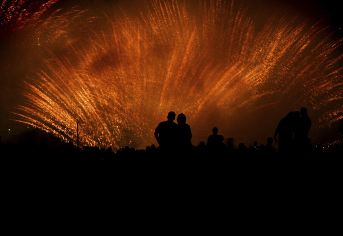 Couple hugging and silhouetted by gold stardust fireworks