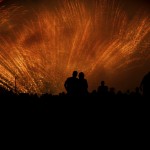 Couple hugging and silhouetted by gold stardust fireworks