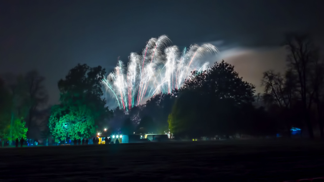 Fluffy silver spinning fireworks bursting over Christchurch Park in Ipswich as part of a professional fireworks display