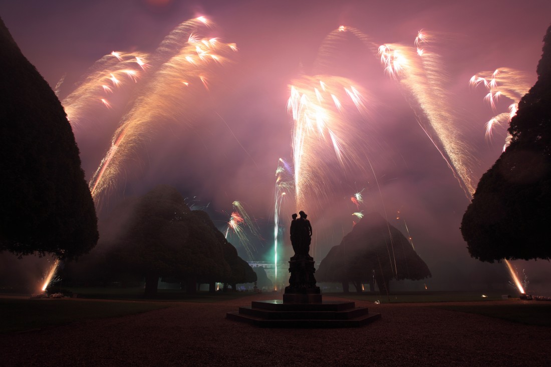 Triangular trees and a statue surrounded by fireworks at Hampton Court Palace