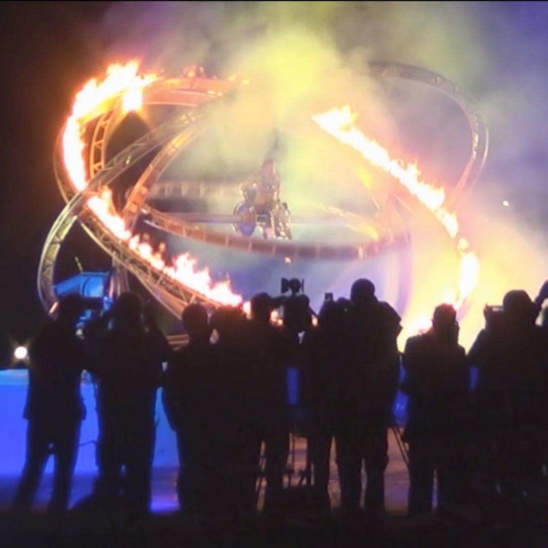 Young female paralympian surrounded by flames and pyrotechnics at the Paralympic torch lighting ceremony