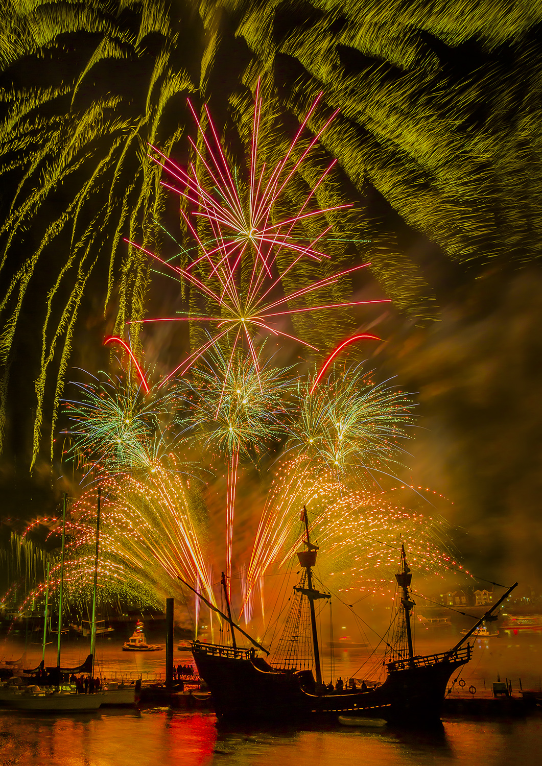 Fireworks display on the River Thames in Woolwich with a Tall Ship silhouetted in the foreground.